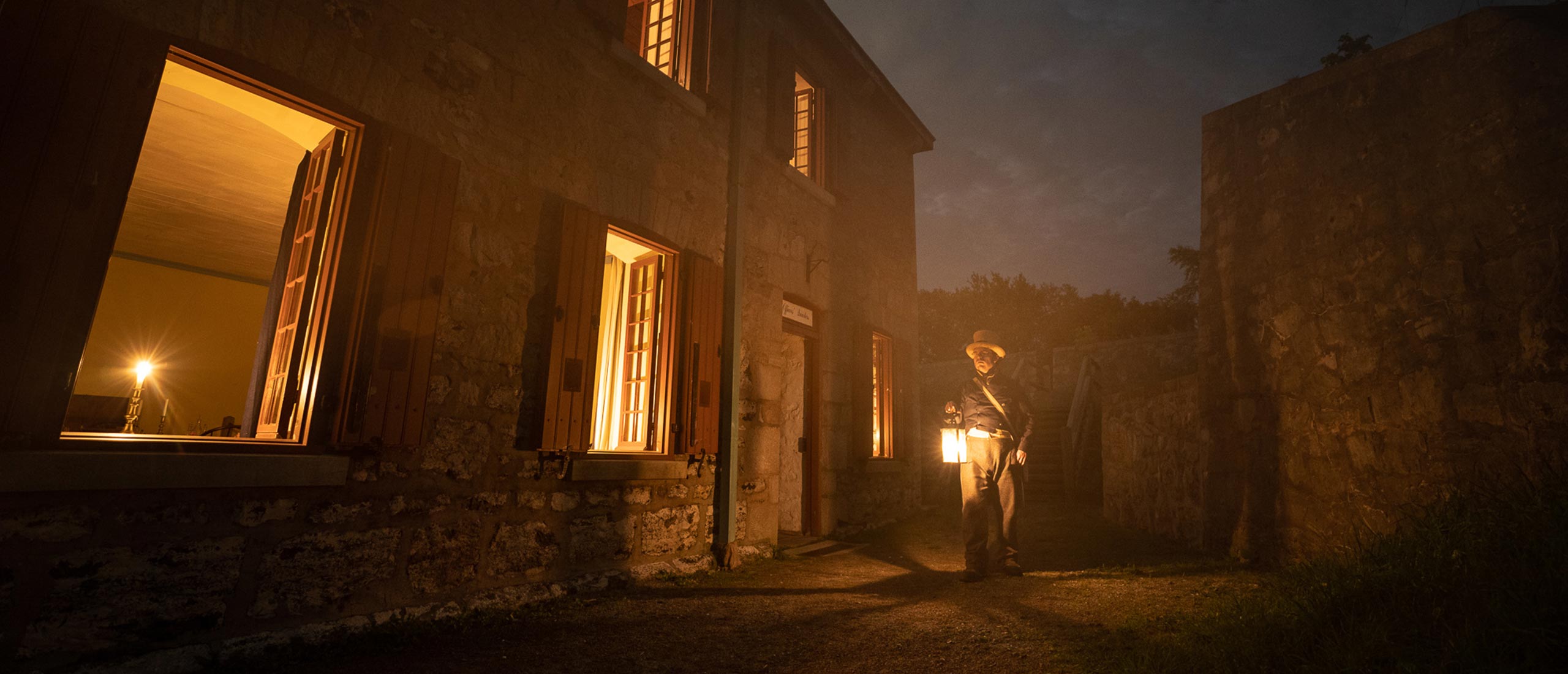 A man directing the ghost tours in the night with a lantern