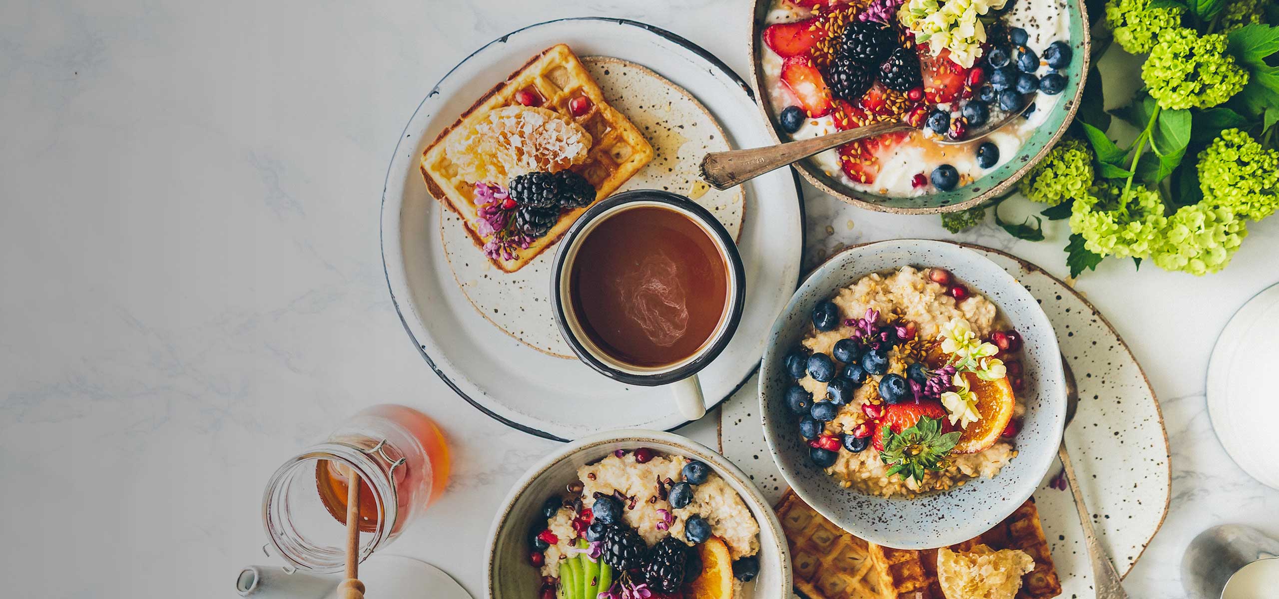 A waffle with various fruits and a cup of coffee.