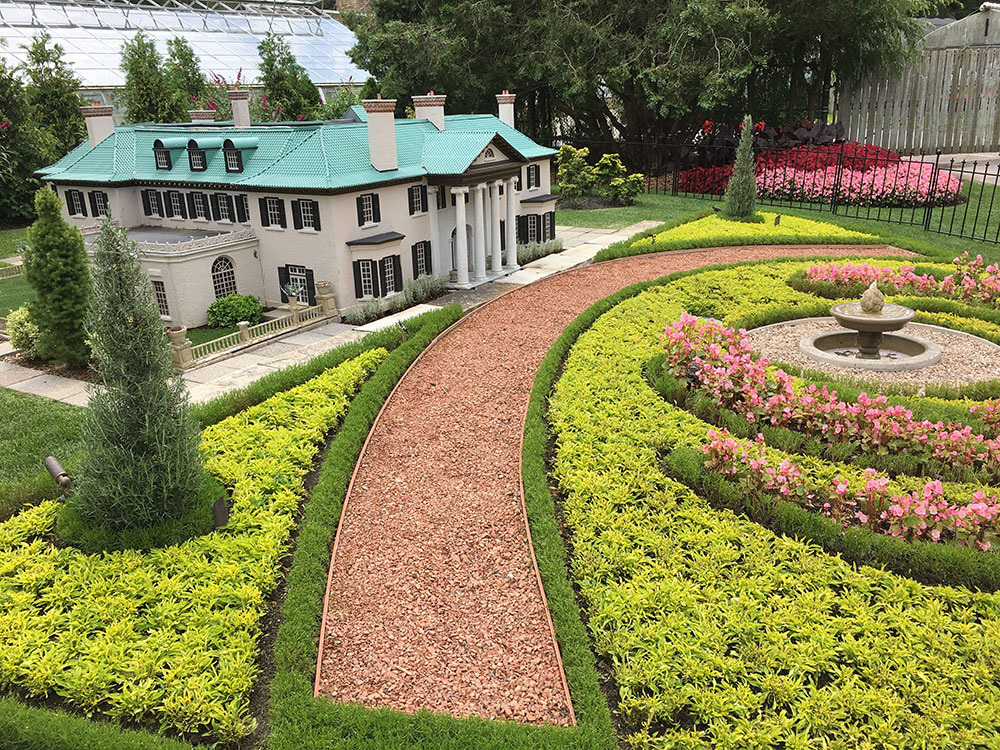 A side view of the Life on Display outdoor exhibit with a miniature house and garden